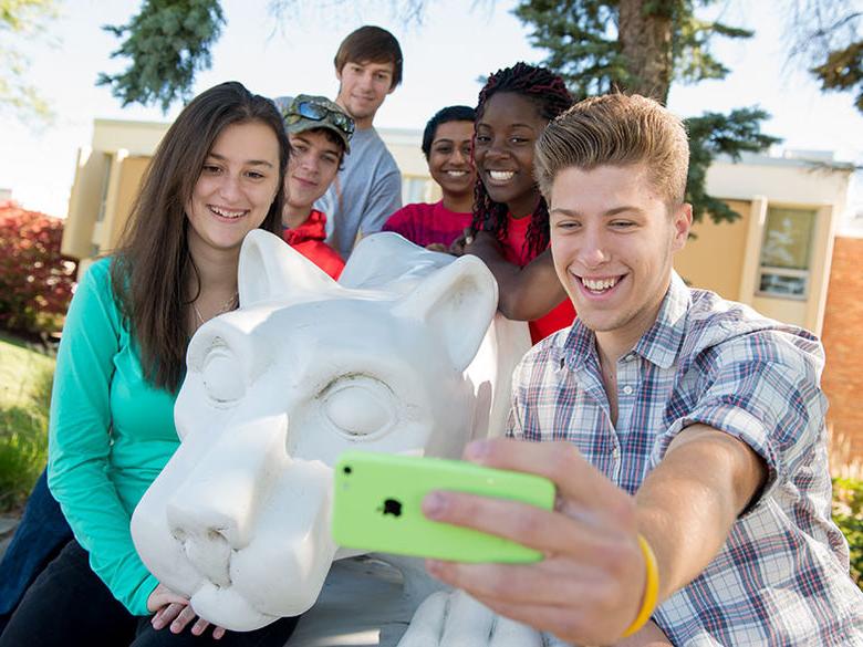 A group of students take a selfie at the campus lion shrine